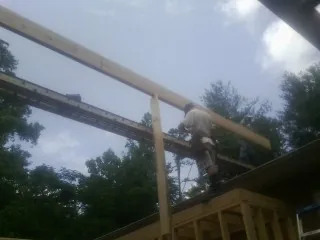 Carpenter setting a ridge beam over a new addition frame — Ice Dam Removal by Roofing Brothers in Townsend