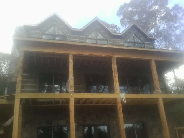 Dormers and porch framing on a large log home under construction — Roof Coating work by our crew in Townsend